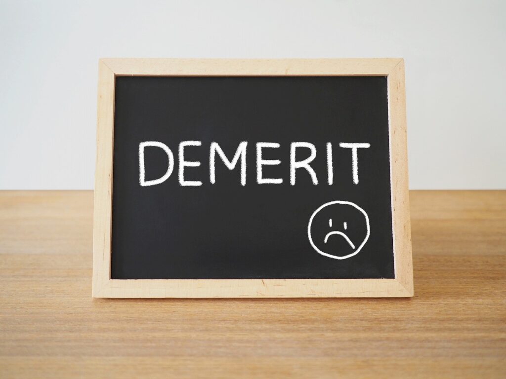 黒板に「DMERIT」と 悲しい顔のマークが書かれている