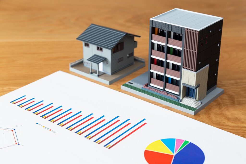 家とマンションの模型の前に置かれている売上・経費・利益の推移を示したグラフ資料