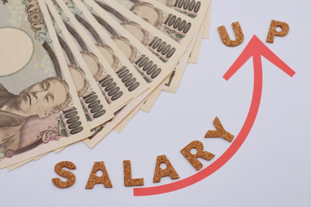 一万円札の束と「SALARY UP」の文字を表す赤い上向き矢印