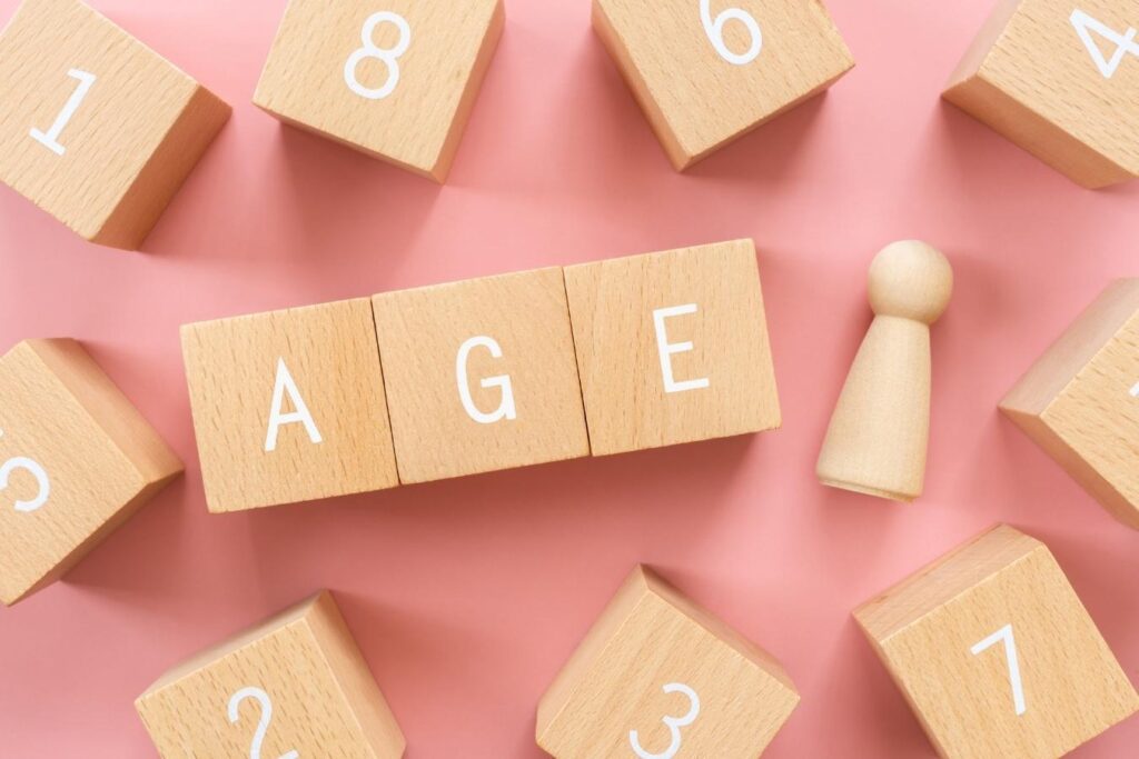 中央に置かれた「AGE」の文字と横にある人形、周りに散らばる数字などのブロック