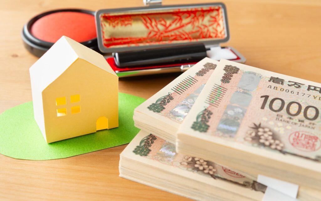 不動産の模型と札束、はんこ