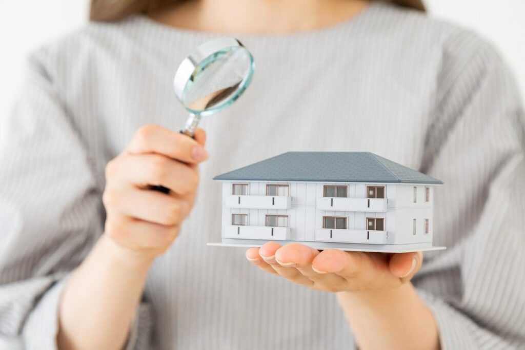 一棟物件の模型と虫眼鏡を持つ若い女性