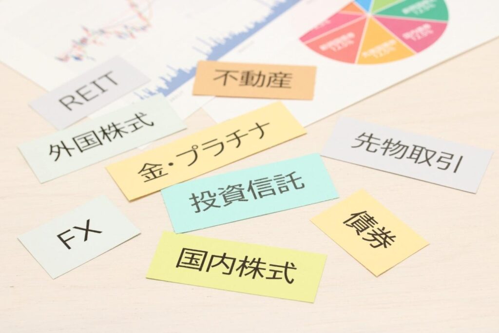 さまざまな投資の種類が書かれたカードと円グラフやチャートが描かれたグラフ資料
