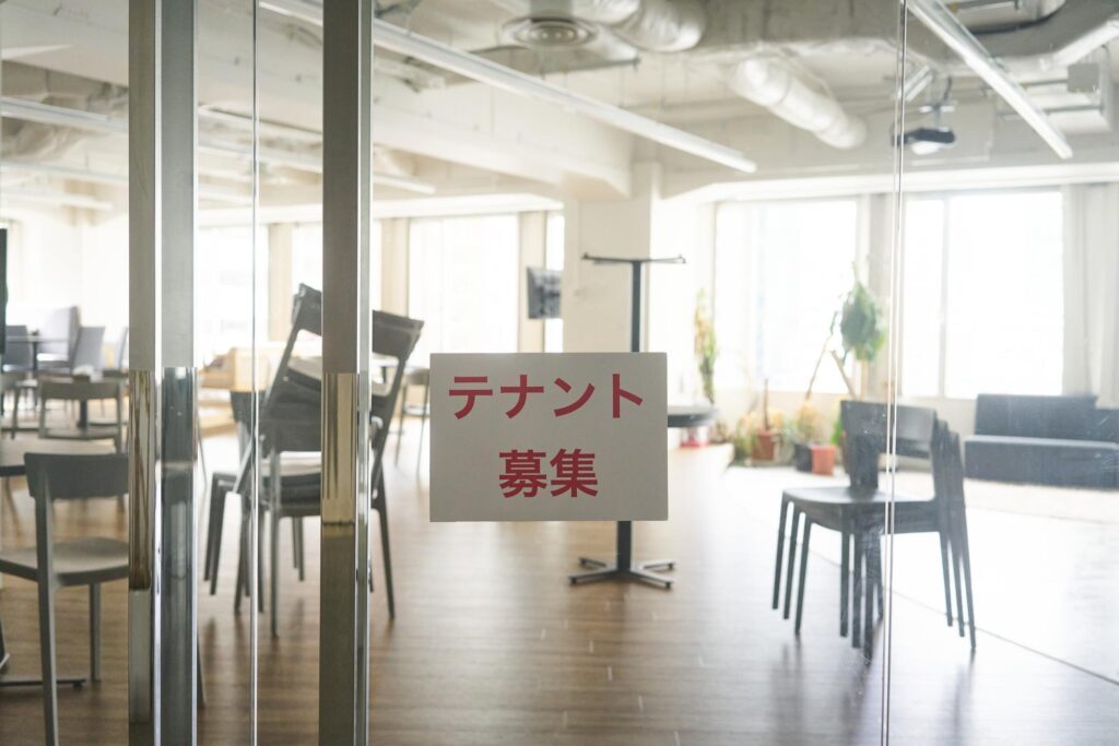 ガラス扉に貼られた『テナント募集』の張り紙と空室の店舗スペースの内観