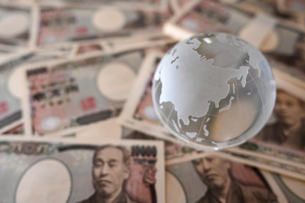 日本円の紙幣の上に置かれたガラス製の地球儀が、国際的な経済や税制の比較を連想させる構図